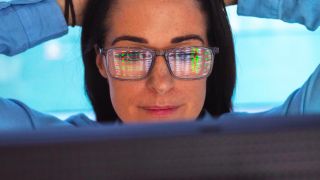 Eine Frau sitzt am Computer, der Bildschirm spiegelt sich in ihrer Brille (Quelle: imago images/Westend61)