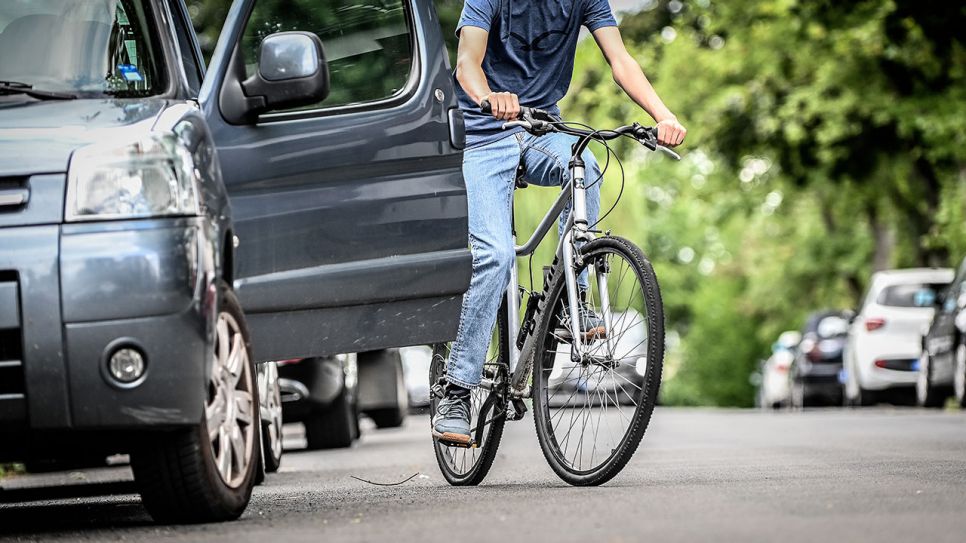 Ein Fahrradfahrer fährt beinahe in eine geöffnete Autotür (Quelle: IMAGO / Funke Foto Services)