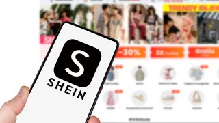Ein Smartphone mit dem Logo der Shopping-Plattform Shein auf dem Display, wird von einer Hand vor einen Computerbildschirm gehalten, auf dem die Shein-Website geöffnet ist (Quelle: picture alliance / Markus Mainka | Markus Mainka)