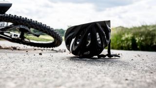 Fahrradunfall, Bild zeigt umgefallenes Fahrrad und Helm auf Landstraße (Quelle: imago images / Fotostand)