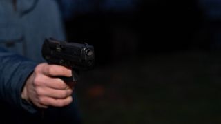 Mordanschlag mit Schusswaffe, Symbolbild Hand hält Waffe im Dunkeln (Quelle: imago images / Michael Bihlmayer)