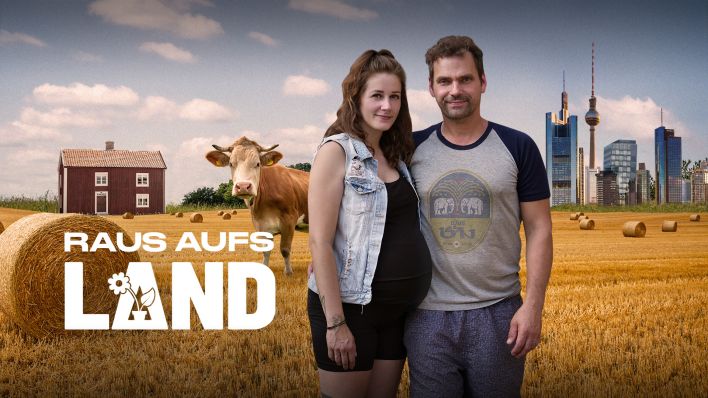 Schauspieler Florian Kleine und seine Frau Nina. Nina ist schwanger. Sie stehen gemeinsam auf einem Feld, im Hintergrund steht eine Kuh und eine Immobilie auf dem Land. Am Horizont sind die Städte Frankfurt (Main) und Berlin zu sehen. Bild: rbb/Hani Sagiv