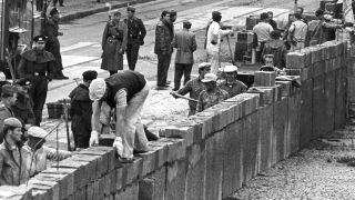 Unter der Aufsicht von bewaffneten Volkspolizisten errichtet eine Ostberliner Maurerkolonne am an der sowjetisch-amerikanischen Sektorengenze am Potsdamer Platz am 18.08.1961 eine Mauer. (Quelle: dpa)