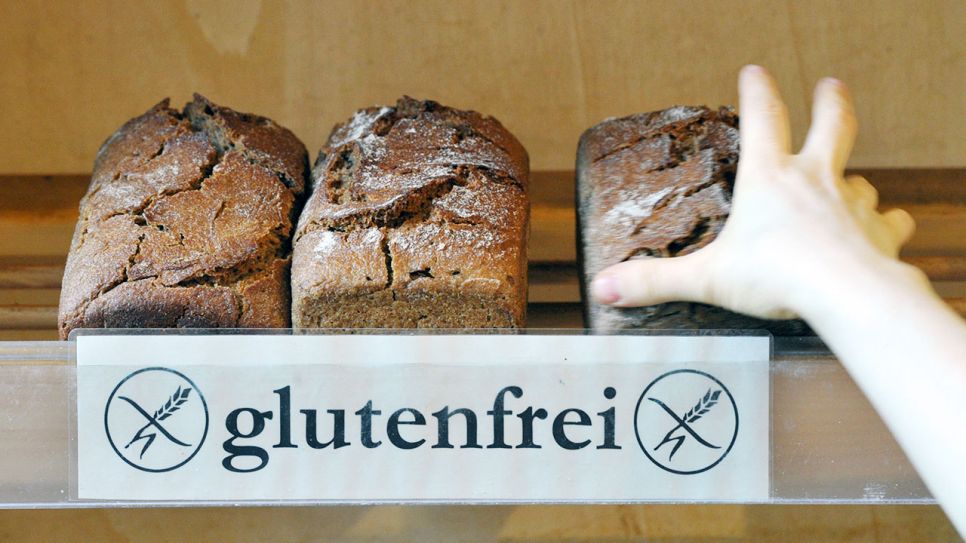 Eine Hand greift nach einem glutenfreien Brot. (Quelle: dpa/Peter Endig)