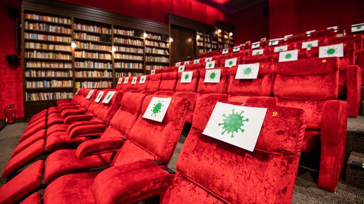 In einem Kinosaal in Hannover sind einzelne Sitze mit Virus-Symbolen abgesperrt (Bild: dpa/Julian Stratenschulte)