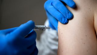 Symbolbild: Eine SARS-CoV-2-Impfung wird per Spritze in einen Oberarm injiziert