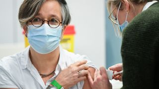 Symbolbild: Eine Mitarbeiterin aus dem Gesundheitswesen wird in einer Praxis geimpft. (Quelle: dpa/P. Wouw)