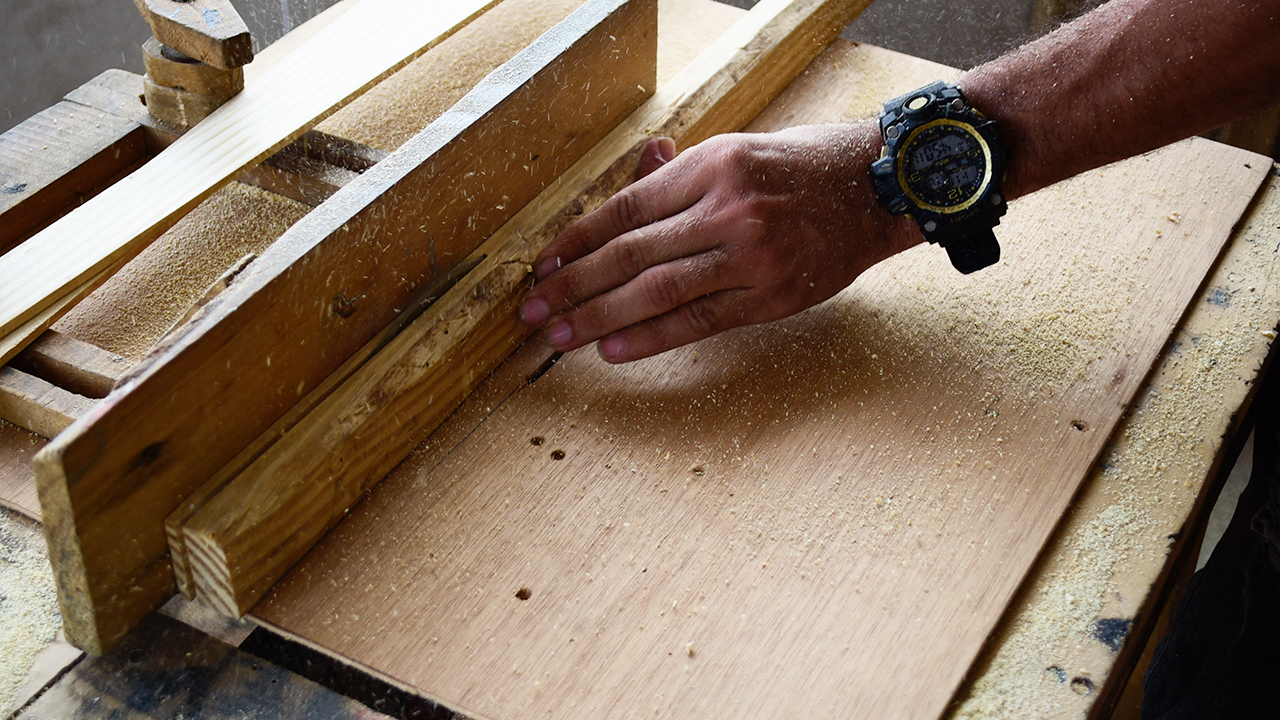 Symbolbild: Ein Mann schneidet ein Stück Holz auf einer Werkbank (Bild: dpa/Edwin Rodriguez Pipicano)