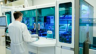 Ein Mitarbeiter hält in einem Coronatest-Labor PCR-Teströhrchen in den Händen. (Quelle: dpa/Uwe Anspach)