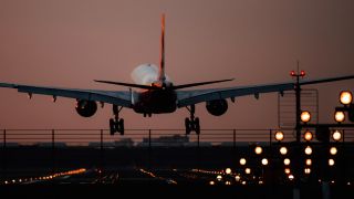 Symbolbild: Ein Verkehrsflugzeug landet nach Sonnenuntergang auf einem Berliner Flughafen. (Quelle: dpa/R. Schlesinger)