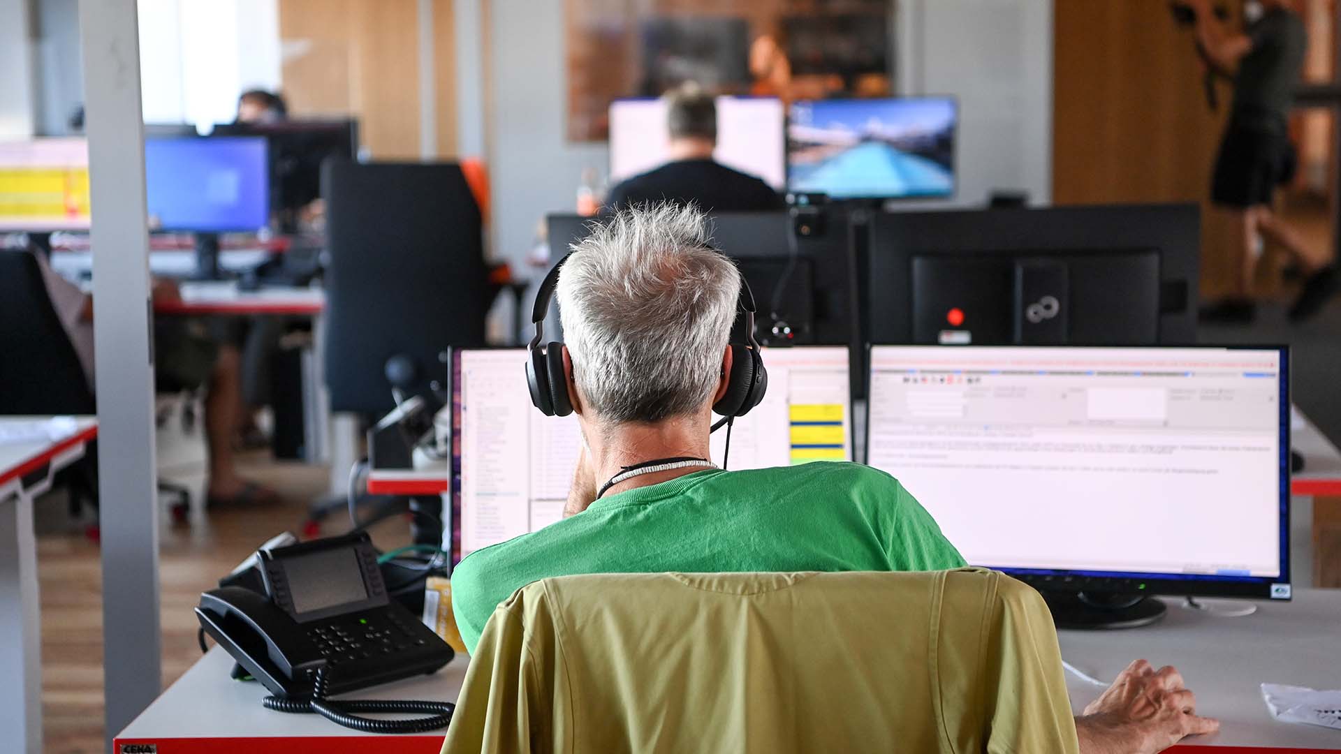 Ein Mitarbeiter im neuen rbb-Newsroom sitzt am Schreibtisch und arbeitet. Bild: dpa/Jens Kalaene
