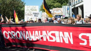 Symbolbild: Corona-Leugner demonstrieren mit Bannern und Deutschlandfahnen auf der Straße. (Quelle: imago images/B. Kessler)