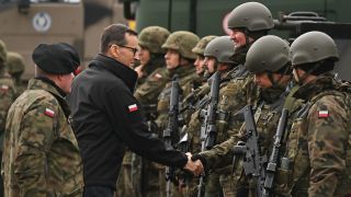 Polens Premierminister schüttelt die Hand eines polnischen Soldaten