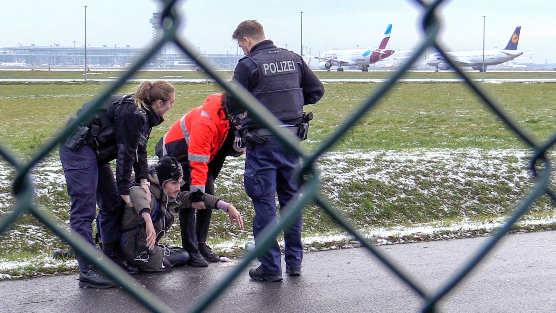 Zwei Beamte der Bundespolizei und ein Sicherheitsmitarbeiter steht mit einem sichergestellten Bolzenschneider an einem Zaun am BER-Flughafen. (Quelle: dpa/Paul Zinken)