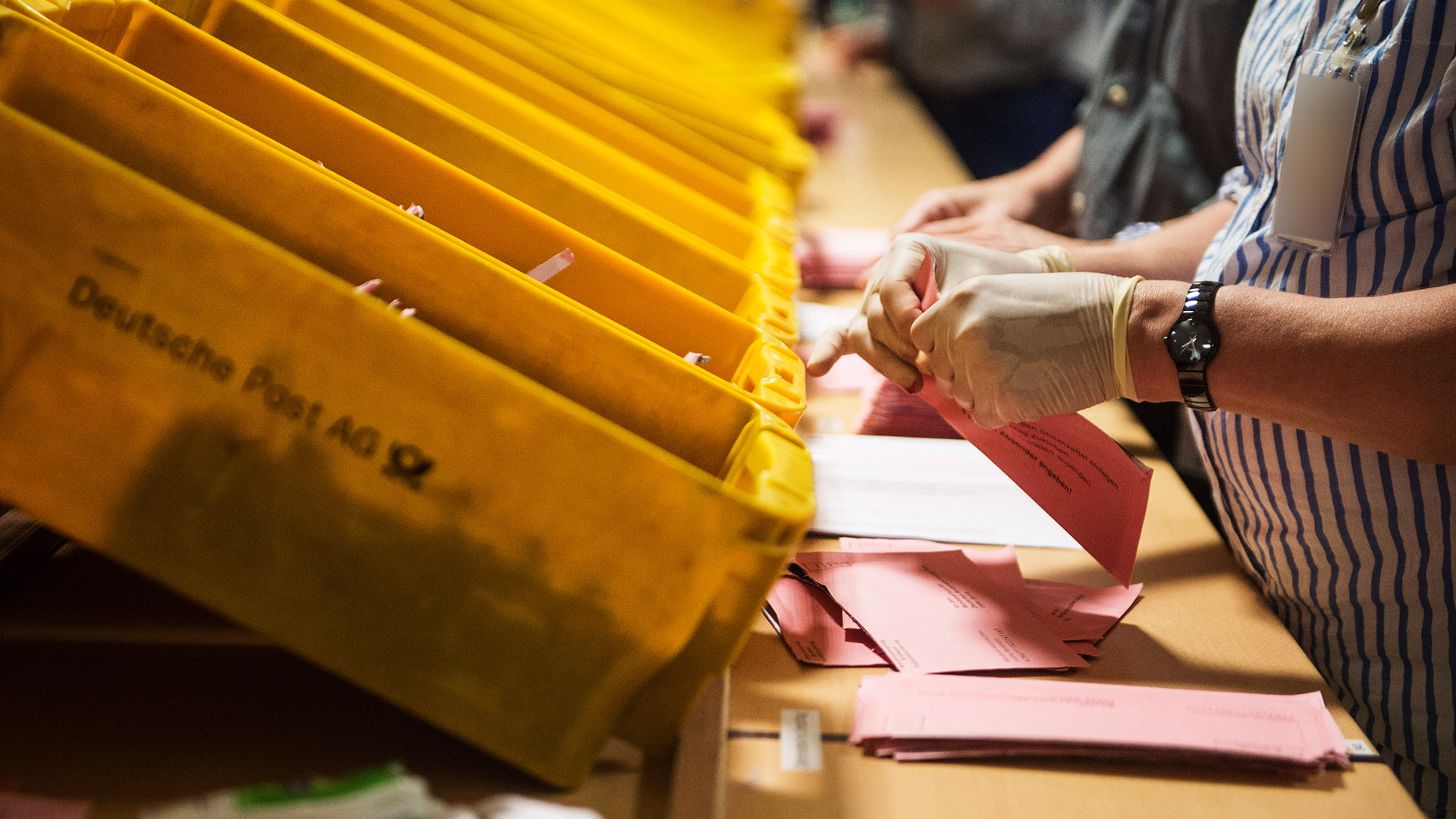 Symbolbild:Eine Wahlhelferin öffnet in einer Lagerhalle in Berlin einen Wahlbrief der Sozialwahl.(Quelle:dpa/L.Mirgeler)