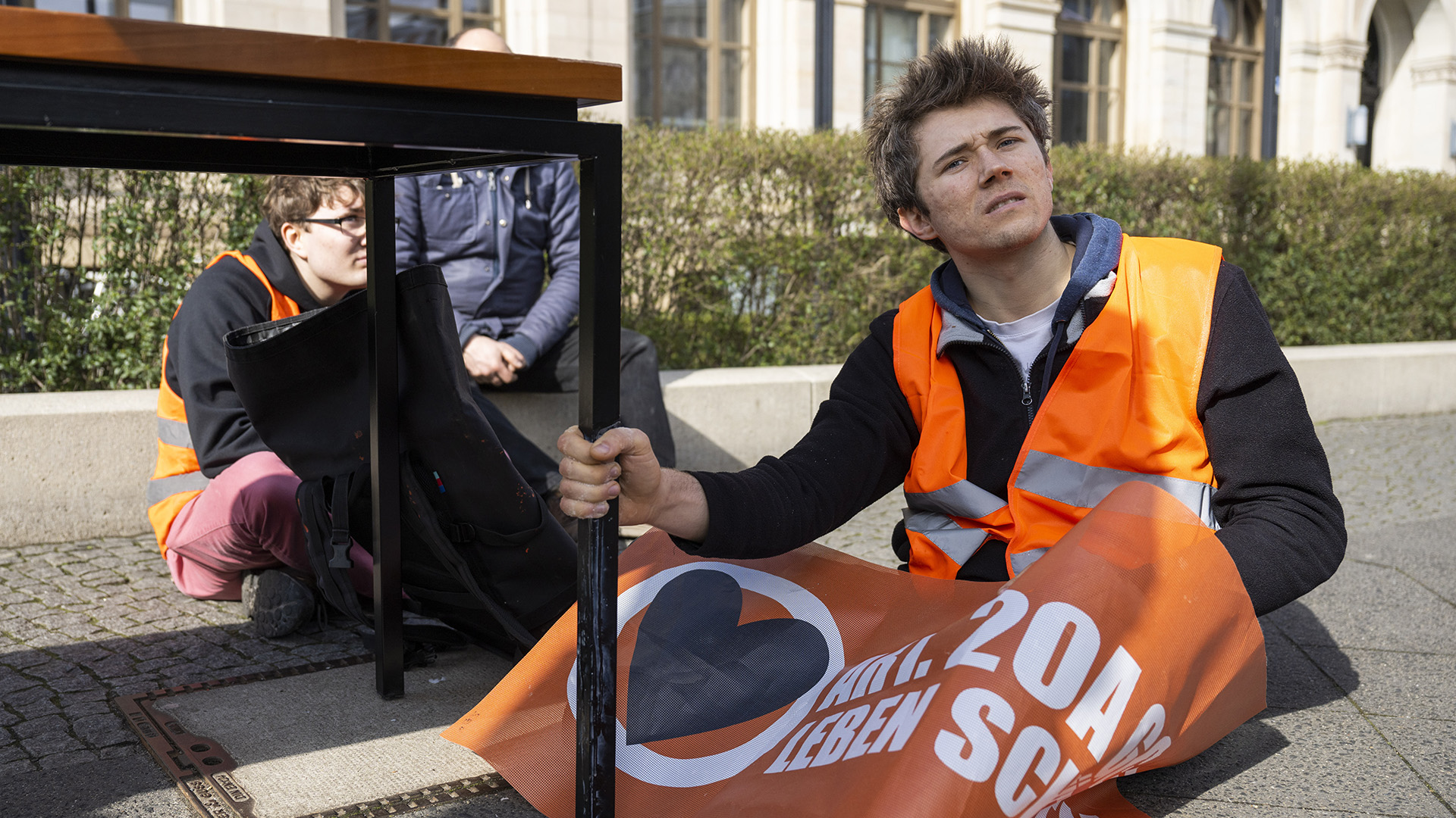 Klimaaktivist Henning Jeschke (r) von der Letzten Generation sitzt am 23.03.2023 bei einer Protestaktion vor dem Bundesverkehrsministerium.