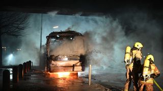Einsatzkräfte der Feuerwehr löschen in der Silvesternacht an der Sonnenallee im Bezirk Neukölln unter einer Durchfahrt einen brennenden Bus. (Quelle: dpa/Paul Zinken)