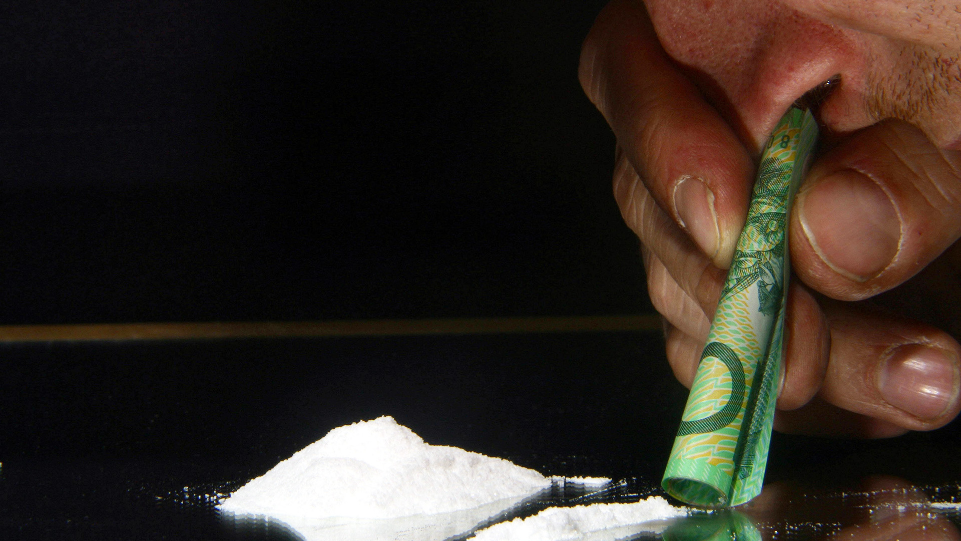 Symbolbild: Mann snifft Kokain durch einen gerollten Geldschein. (Quelle: dpa/blickwinkel)