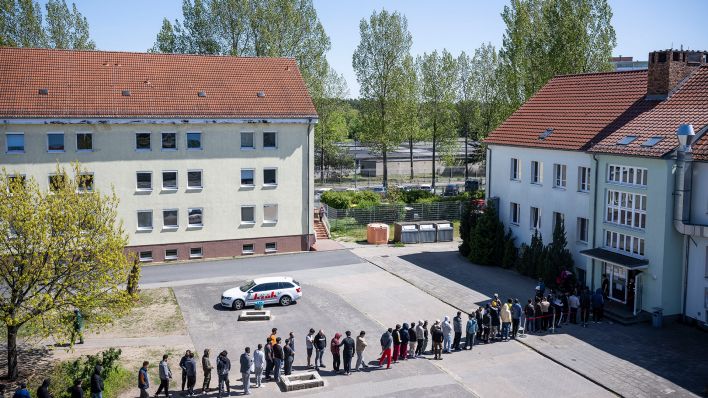 Archivbild: Migranten stehen in einer Schlange in der Erstaufnahme-Einrichtung (EAE) des Landes Brandenburg in Eisenhüttenstadt. (Quelle: dpa/H. Albert)