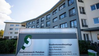 Ein Schild mit der Aufschrift "Studentenwerk Potsdam" und "Studentenwohnanlage" steht vor dem Eingang zu dem Studentenwohnheim auf dem Campus Golm der Universität Potsdam. (Quelle: dpa/Monika Skolimowska)