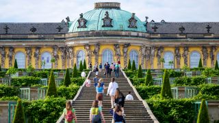 Symbolbild: Zahlreiche Besucher stehen im Park Sanssouci auf der Treppe vor dem Schloss Sanssouci. (Quelle: dpa/Monika Skolimowska)