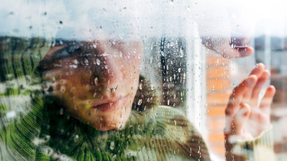 Symbolbild: Eine Person mit nachdenklichem Blick steht am Fenster. (Quelle: imago images/Alberto Menendez)