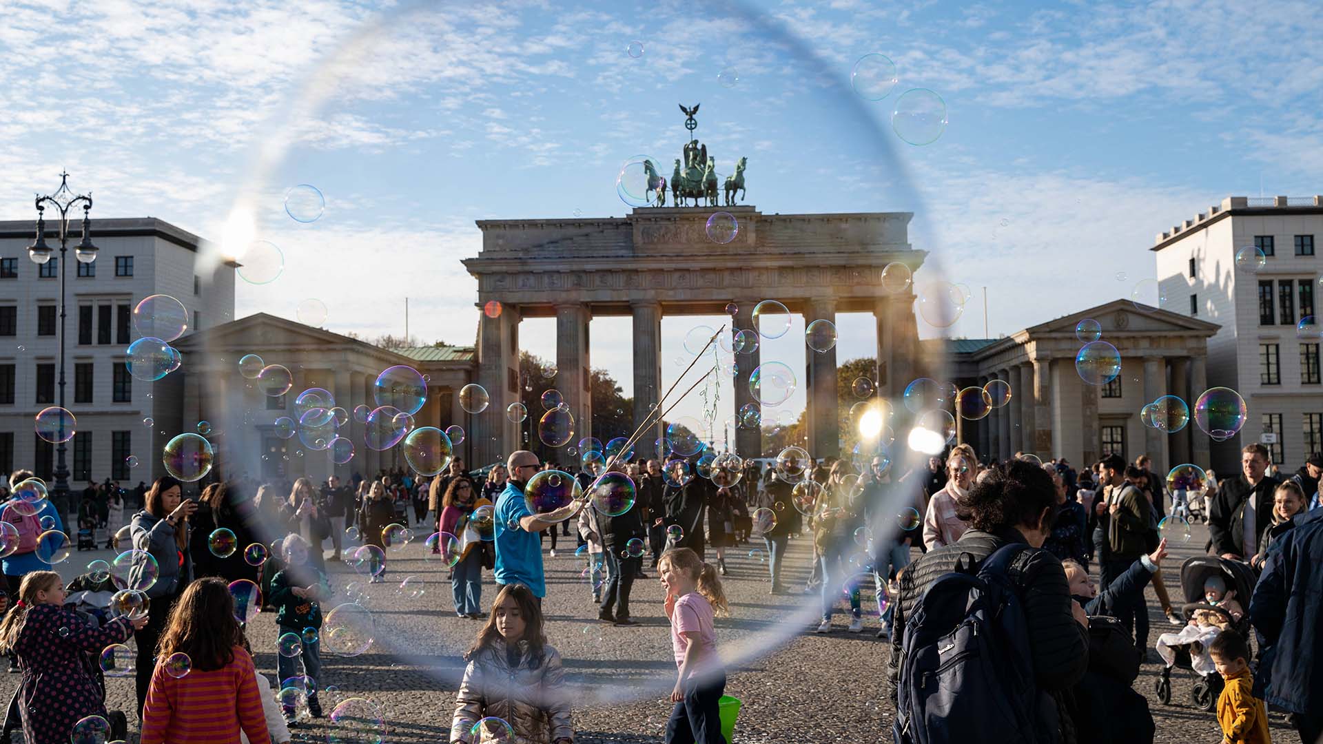 Symbolbild: Ein Strassenkuenstler blaest Seifenblasen mit Schlaufen an einer Schnur auf dem Pariser Platz vor dem Brandenburger Tor im Bezirk Mitte. (Quelle: dpa/Schülke)