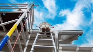 Symbolbild:EIn Arbeiter steht auf einer Leiter an einem Baugerüst.(Quelle:imago images/Zoonar)