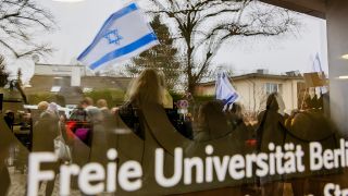 Symbolbild: Eine Israel-Flagge spiegelt sich bei einem stillen Protest einer Initiative für die Sicherheit jüdischer Studierender in einer Scheibe der Freien Universität Berlin am 09.02.2024.(Quelle: picture alliance/Christoph Soeder)