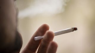 Ein Mann raucht einen Joint. Das Konzept der Ampel-Koalition sieht vor, dass in Deutschland der Besitz von maximal 25 Gramm Cannabis und der Eigenanbau von höchstens drei Pflanzen künftig straffrei sein sollen. (Quelle: dpa/Hannes P Albert)