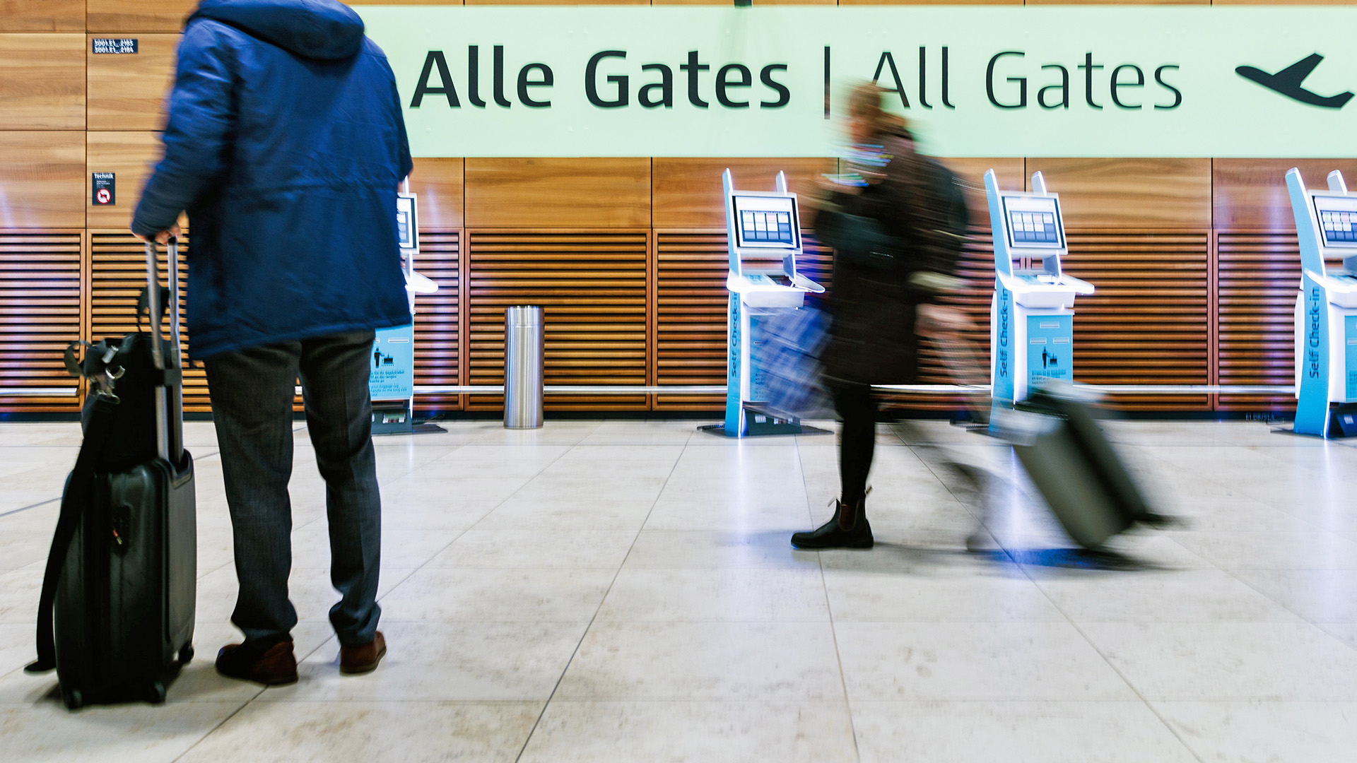 Archivbild: Fluggaste ziehen am 28.02.2024 Rollkoffer durch die Halle von Terminal 1 des Flughafens BER. (Quelle. dpa/Carsten Koall)