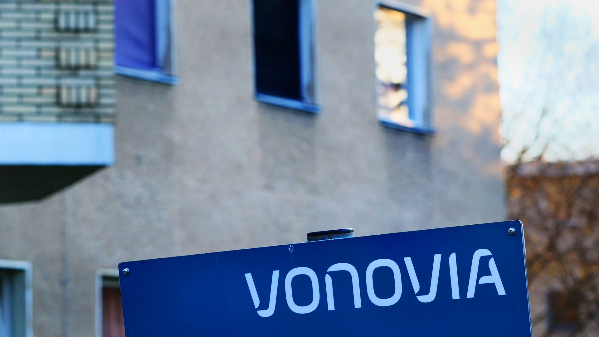 Vor einem einfachen Mietshaus steht ein Schild mit dem Vonovia-Logo. (Quelle: dpa/Wolfram Steinberg)
