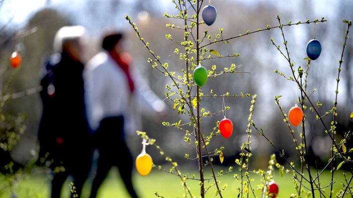 Zwei Menschen laufen an aufgehängten Ostereiern vorbei im Britzer Garten. Die Parkanlage ist seit Anfang März wieder für Besucher geöffnet. (Foto: dpa)