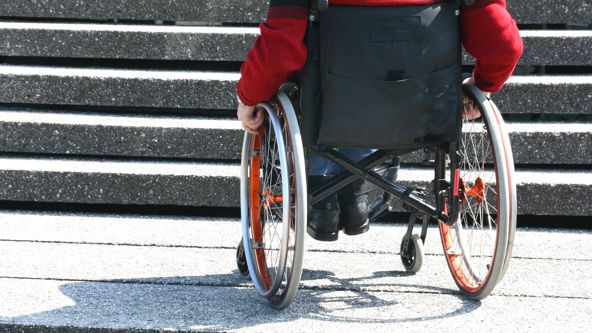Symbolbild: Mann im Rollstuhl verzweifelt und wartend auf einer Treppe. (Quelle: dpa/blickwinkel)