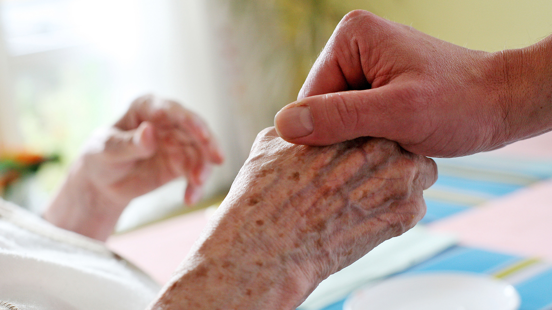 Symbolbild: Ein Pfleger hält in einem Pflegeheim die Hand einer Bewohnerin.(Quelle: dpa/Oliver Berg)