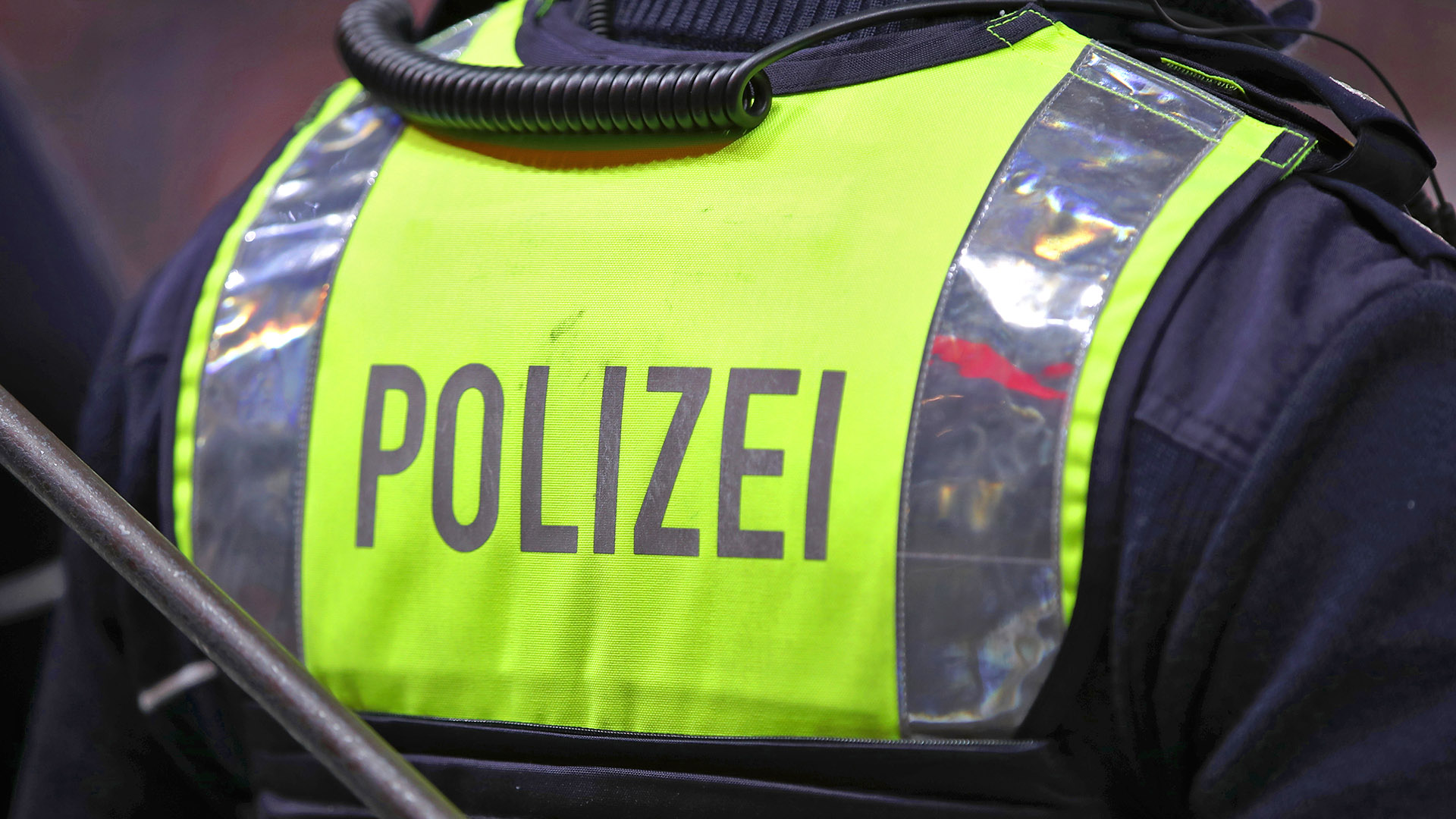 Symbolbild:Ein Polizist auf Streife mit gelber Schutzweste und Schriftzug POLIZEI auf der Weste.(Quelle:imago images/M.Koch)