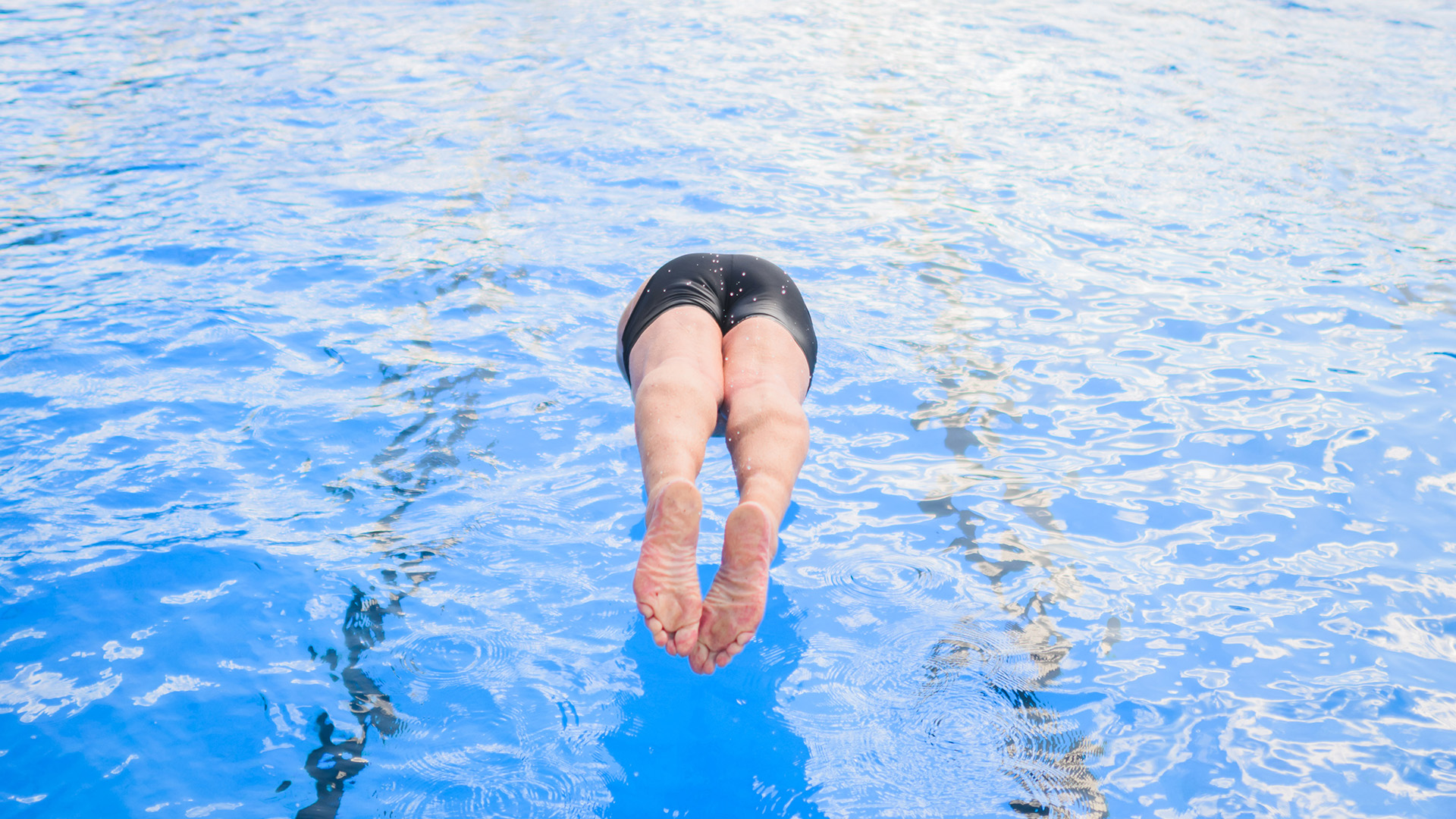 Ein Badegast springt im Freibad Annabad in Brandenburg mit einem Kopfsprung ins Wasser.