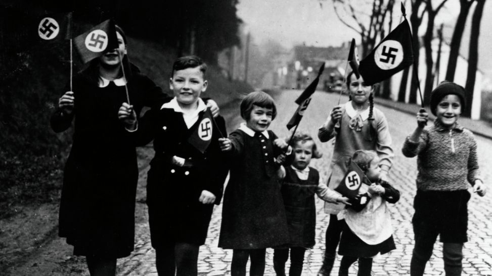 Kinder gehen mit Hakenkreuzfahnen in der Hand spazieren. Propagandafoto für die Presse. (Bild: rbb/Scherl/Süddeutsche Zeitung Photo)